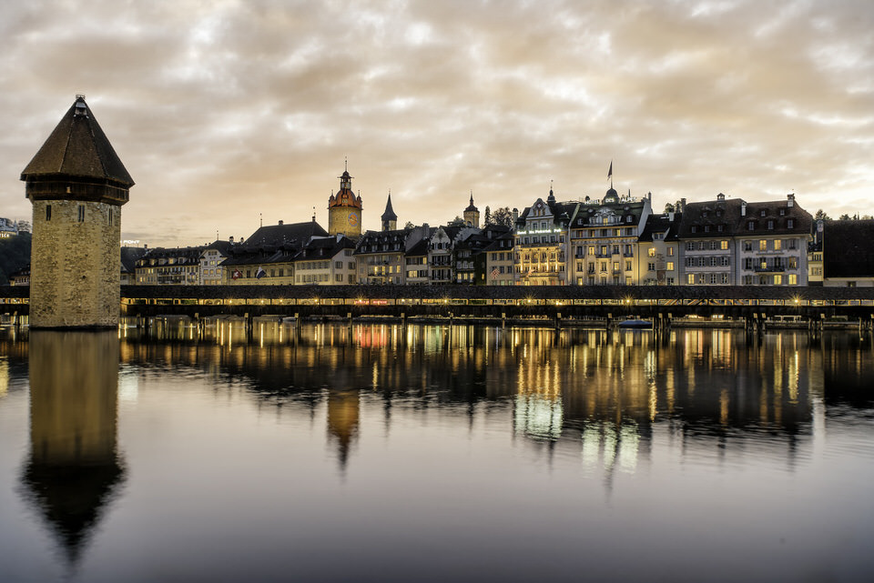 Chapel Bridge reflecting in the river with golden hour sky in Lucerne