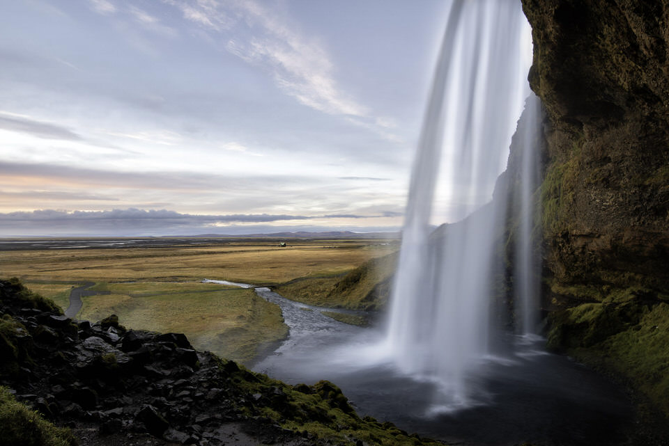 Seljalandsfoss waterfall in Iceland cascading with open plains in the background at sunrise